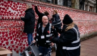 Volunteers hang lights on The National Covid Memorial Wall, dedicated to those who lost their lives to Covid-19, on the bank of the River Thames in London on December 20, 2024. (Photo by Benjamin Cremel / AFP)