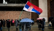 A Belgrade student waves a Serbian national flag as he blocks a major city intersection to silently honour the 15 victims of the tragedy at the Novi Sad railway station November 2024, in Belgrade, on December 25, 2024. (Photo by Andrej ISAKOVIC / AFP)

