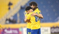Al Gharafa's Ferjani Sassi celebrates with Ahmed Al Ganehi after scoring a goal.