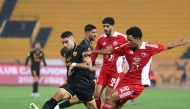 Al Arabi players challenge an Al Qadsia player during the match.