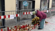 A woman stands at a makeshift memorial of candles and flowers placed on February 16, 2025 at the site where a man randomly attacked passers-by with a knife and stabbed to death a teenager and wounded five other people in Villach, Austria. Photo by GERD EGGENBERGER / APA / AFP