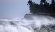 People watch as waves lash against the shore in Saint-Denis de la Reunion, on the French overseas territory island of La Reunion, as the tropical cyclone 