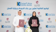 Assistant Undersecretary for National Manpower Affairs in the Private Sector at the Ministry of Labour Shaikha Abdulrahman Al Badi (right) and Chief Retail Banking Officer at Doha Bank Braik Ali Al Marri exchanging documents after signing the agreement.