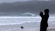 A resident takes pictures with a mobile phone of massive waves stirred by tropical cyclone Alfred at Byron Bay's Main Beach on March 5, 2025. (Photo by David Gray / AFP)