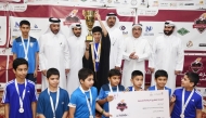 Al Adaam players pose with officials as their captain lifts the trophy. 