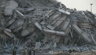 Rescue workers walk past debris of a construction site after a building collapsed in Bangkok on March 28, 2025, following an earthquake. Photo by Lillian SUWANRUMPHA / AFP