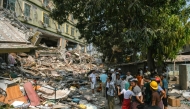 People look on as teams of rescue workers attempt to free residents trapped under the rubble of the destroyed Sky Villa Condominium development in Mandalay on March 29, 2025. (Photo by Sai Aung Main / AFP)