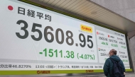 A man looks at an electronic board displaying the numbers on the Tokyo Stock Exchange, showing the market down over four percent, in early afternoon trading in Tokyo on March 31, 2025. (Photo by Richard A. Brooks / AFP)
