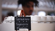 A sign reads Canadiano instead of Americano coffee at the booth of Partner country Canada at the Hannover Messe industrial trade fair for mechanical and electrical engineering and digital industries, on March 31, 2025 in Hanover, northern Germany. (Photo by RONNY HARTMANN / AFP)
