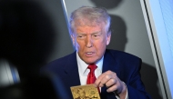 US President Donald Trump holds the $5 million dollar Gold Card as he speaks to reporters while in flight on board Air Force One, en route to Miami, Florida on April 3, 2025. Photo by MANDEL NGAN / AFP