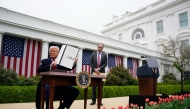 President Donald Trump displays an executive order after announcing a plan for tariffs on imported goods on Wednesday with staff secretary Will Scharf watching. (Photo by Jabin Botsford/The Washington Post)

