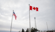 (Files) The Canadian and US flags fly near the Canada-US border in Blackpool, Quebec, Canada, on February 2, 2025. (Photo by Andrej Ivanov / AFP)