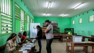 Voters receive their ballot papers from electoral officials at the Lycee Leon Mba polling station in Libreville on April 12, 2025 during Gabon's presidential election. (Photo by Daniel Beloumou Olomo / AFP)