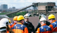 British Steel staff members talk before posing for a photograph with Britain's Deputy Prime Minister Angela Rayner (unseen) with the blast furnaces in the background, during her visit to British Steel's site in Scunthorpe, northern England on April 14, 2025. (Photo by Peter Byrne / POOL / AFP)
