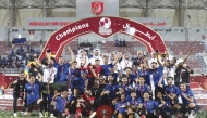 Al Sailiya's players and officials celebrate with the trophy.
