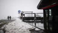 People walk past snow-covered chalets after heavy snowfall at the Aravis Pass (Col des Aravis), near La Clusaz in east-central France, on April 17, 2025. Photo by OLIVIER CHASSIGNOLE / AFP