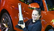 Latvia’s Jelena Ostapenko celebrates with the trophy in front of the winner's car after winning the final match against Belarus’ Aryna Sabalenka (unseen) at the Women's Tennis Grand Prix WTA tournament in Stuttgart, southwestern Germany, on April 21, 2025. (Photo by THOMAS KIENZLE / AFP)