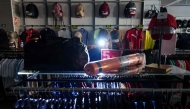 A saleswoman at a sports store works with a light on her head in Burgos on April 28, 2025, during a massive power cut affecting the entire Iberian peninsula and the south of France. (Photo by CESAR MANSO / AFP)
