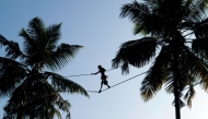 A worker walks on a rope between two coconut trees to collect tree sap in Negombo, about 30 kilometers north of Colombo, Sri Lanka, April 26, 2025. (Photo by Ajith Perera/Xinhua)