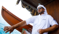 A competitor participates in a line-fishing competition aboard a wooden dhow during the Senyar festival off the coast of Sealine beach, south of Doha on April 21, 2025. Photo by Karim JAAFAR / AFP
