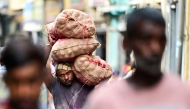 A labourer carries sacks of onions at a market in Colombo on April 30, 2025. (Photo by Ishara S. KODIKARA / AFP)

