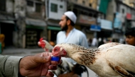 A man pours water for a chicken on a hot summer day in Rawalpindi on May 23, 2025. (Photo by Farooq Naeem / AFP)