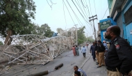 Pakistani policemen look on as workers remove a fallen railway tower after a storm in Multan on May 28, 2025. (Photo by Shahid Saeed Mirza / AFP)