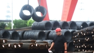 A worker walks past rolls of steel at a steel market in Hangzhou, in eastern China's Zhejiang province on June 4, 2025. (Photo by AFP) 