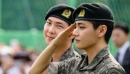K-pop boy band BTS member V (R) salutes as RM looks on at an outdoor sporting facility in Chuncheon on June 10, 2025. (Photo by Anthony Wallace / AFP)