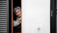 (Files) This file picture taken on January 16, 2018 shows Kimiko Nishimoto posing next to a picture of her on the sliding window of her house. (Photo by Behrouz Mehri / AFP)