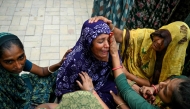 Women mourn their relatives killed the previous day after Air India flight 171 crashed in a residential area, whilst waiting outside hospital mortuary in Ahmedabad on June 13, 2025. (Photo by Punit PARANJPE / AFP)