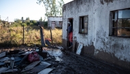 A resident of an informal settlement sweeps mud out of her dwelling after a flood near Mthatha on June 12, 2025. (Photo by Emmanuel Croset / AFP)