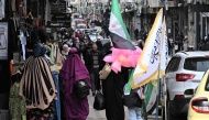 File: People walk past shops in Homs on February 10, 2025. (Photo by Louai Beshara / AFP)


