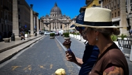 People walk while eating ice cream on a hot summer day in Rome near the Vatican on June 28, 2025. (Photo by Tiziana Fabi / AFP)