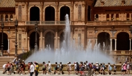 File: A group of schoolchildren on a excursion cool off walking along a fountain at the Plaza Espana square in Seville on April 26, 2023. (Photo by Cristina Quicler / AFP)