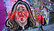 A man walks past a mural by street artist Jarrod Grech of Erin Patterson - now stamped with a guilty sign - of the Australian woman found guilty of murdering three members of her husband's family with a toxic mushroom-laced beef Wellington lunch, in Melbourne on July 9, 2025. Photo by William WEST / AFP