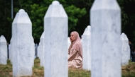 A woman reacts as she sits among gravestones at the memorial cemetery in the village of Potocari, near the eastern Bosnian town of Srebrenica, on July 11, 2025, on the 30th anniversary of the Srebrenica massacre. Photo by Andrej ISAKOVIC / AFP.
