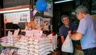 A rice mill shopowner (2nd R) tends to a customer in Tokyo on July 18, 2025. Photo by Kazuhiro NOGI / AFP