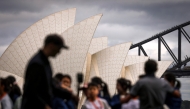 Tourists pose for photographs in front of the Sydney Opera House and Sydney Harbour Bridge on March 31, 2025. Photo by DAVID GRAY / AFP