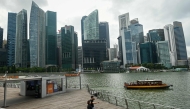People walk as a cruise boat moves along the water at Marina Bay in Singapore on January 27, 2025. (Photo by Roslan RAHMAN and ROSLAN RAHMAN / AFP)

