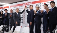 Japan's Prime Minister Shigeru Ishiba (centre R) and LDP vice president Yoshihide Suga (4th L) place a flower on the name of a candidate who is certain to win with other party members, at the vote counting centre at Liberal Democratic Party (LDP) headquarters in Tokyo on July 20, 2025.  (Photo by JIJI Press / AFP)