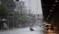 A cyclist crosses a flooded street in Manila on July 22, 2025, after heavy rains caused floodings enhanced by monsoon. Photo by Ted ALJIBE / AFP