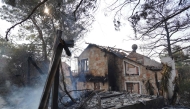 Smoke rises from the embers of a burnt house as firefighters battle a forest fire in the Cypriot village of Souni, in the Limassol province, on July 24, 2025. (Photo by Etienne TORBEY / AFP)