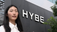 A woman walks past the signage for HYBE, the agency behind K-pop megastars BTS, displayed outside the company's headquarters in Seoul on July 24, 2025. Photo by Jung Yeon-je / AFP