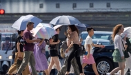 People cross a street under the hot sun in Tokyo on July 24, 2025. (Photo by Kazuhiro NOGI / AFP)
