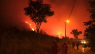 Firefighters attempt to extinguish a wildfire as smoke and flames rise from a forested area in the Gursu district of Bursa early on July 27, 2025. (Photo by ONUR YURTSEVER / AFP)