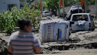 A man looks at flood damaged cars seen following heavy rains over the past few days in Huairou district, on the outskirts of Beijing on July 30, 2025. Photo by Pedro Pardo / AFP