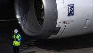 Workers stand next to a Rolls Royce aircraft engine on a passenger plane at Tokyo's Haneda airport on January 29, 2021. Photo by CHARLY TRIBALLEAU / AFP