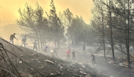 This handout photograph taken and released on August 8, 2025 by Turkish news agency DHA (Demiroren News Agency) shows people working to extinguish wildfire in Canakkale, northwestern Turkey in the Marmara region. (Photo by HANDOUT / DHA (Demiroren News Agency) / AFP)