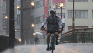 People cycle and walk in heavy rain in the city of Kumamoto, Kumomoto prefecture, southwestern Japan, on August 11, 2025. Photo by JIJI Press / AFP